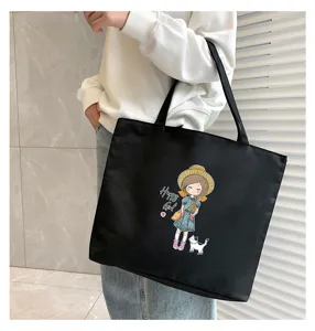 Detail view of the black canvas tote bag featuring a cute cartoon girl print design.