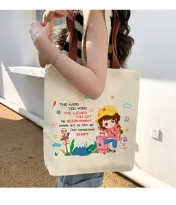 Détail de sac cabas en toile avec impression de fille de dessin animé et slogan.