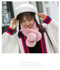 Close-up of cute pink plush scarf with fluffy pom-poms, cozy winter fashion detail shot.