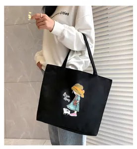 Detailed view of large black canvas tote bag with cute cartoon girl graphic in daily use.