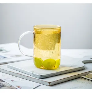 Primo piano dettagliato della tazza in vetro ambrato elegante con manico e uva verde fresca.