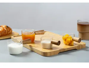 Detailansicht japanischer kleiner Glasmilchbecher mit Holzgriffen auf einem Holztablett.