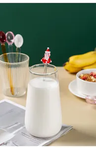 Close-up detail of cute Christmas Santa glass stirring spoon in a glass of milk on table.