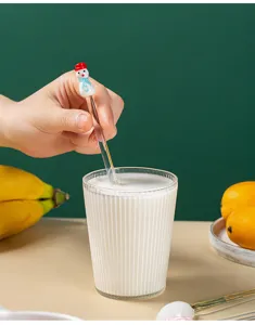 Detailed shot of a cute snowman glass stirring spoon in a cup with milky drink, aesthetic.
