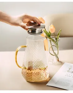 Heat-resistant glass pitcher with hammer texture, gold handle and stainless steel infuser lid.
