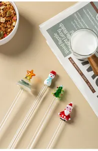 Detailed shot of cute Christmas glass stirring spoons featuring snowman and tree tops.
