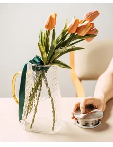 Detail view of heat-resistant glass teapot with hammer texture, golden handle and filter lid.