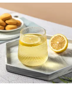 Détail de tasse en verre texturée avec motif losanges et rondelle de citron sur plateau