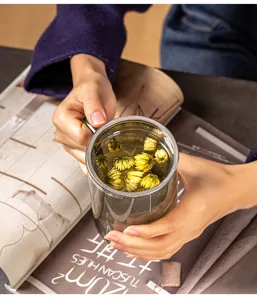 Gros plan d'une tasse à thé en verre avec infuseur en inox rempli de fleurs jaunes.