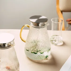 Heat-resistant glass water pitcher with hammer texture, gold handle and stainless steel lid.
