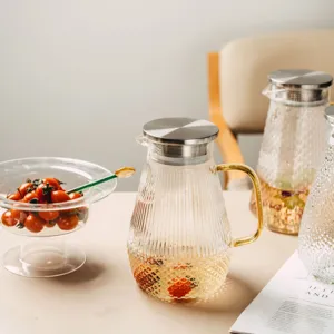 Heat-resistant glass water pitcher and tea kettle with stylish golden handle and metal lid.