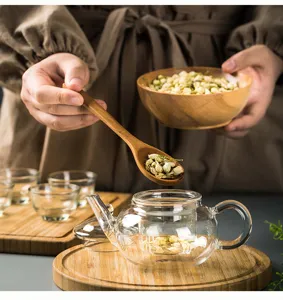 Set da tè in vetro trasparente con vassoio e cucchiaio in legno, ideale per infusi di fiori.