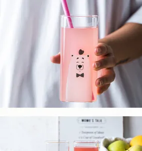 Detailed shot of a cute square glass cup with bear print, held in hand with fruit prop.