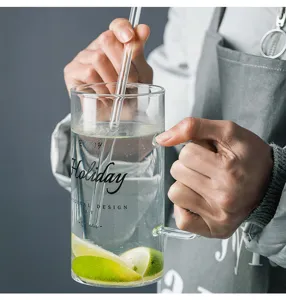 Clear glass mug with straw, letter print and handle, ideal for cold drinks and office water use.
