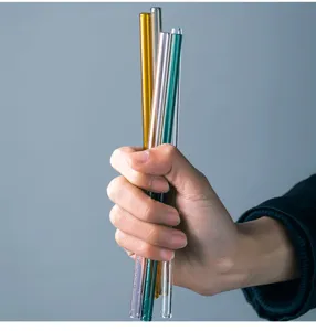 Detailed close-up shot of colorful glass straws held in hand, showing smooth and transparent texture.
