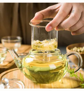 Dettaglio teiera in vetro con infusor in vetro borosilicato resistente al calore con fiori.