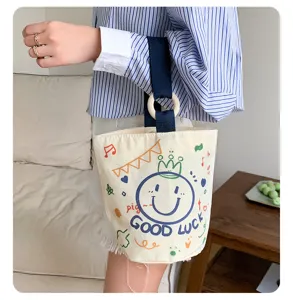 Canvas bucket bag detail shot, cute smiley face print, durable fabric and wooden ring handle.
