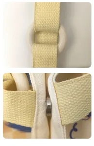 Canvas bag detail shot showing yellow strap, wooden ring, and magnetic snap closure.