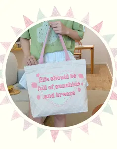 Detailed view of the cute canvas tote bag showcasing the pink heart lace graphic.