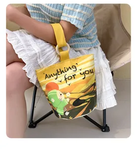 Detailed view of the yellow canvas bucket bag with cute cartoon print and wooden ring handle.