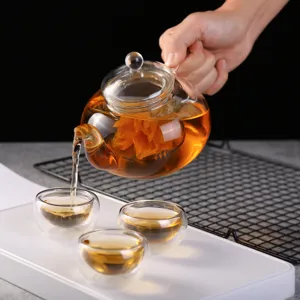 Théière en verre transparent avec infuseur et tasses à double paroi pour thé fleuri.