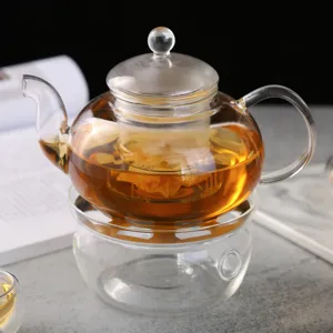 Théière en verre transparente avec infuseur et base chauffante pour thé et usage.