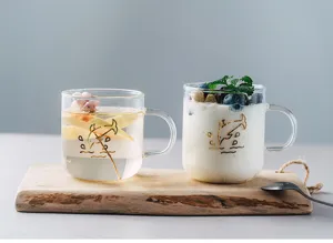 Clear glass cup detail view with gold dolphin print, heat resistant design, ideal for drinks.
