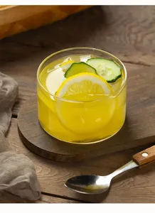 Close-up detail of clear glass dessert bowl with lemon drink on a rustic wooden cutting board.