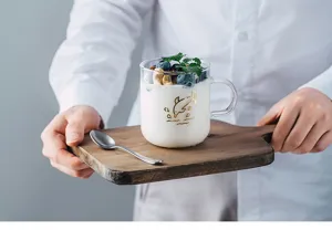 Close-up of clear heat-resistant glass mug with gold dolphin pattern holding yogurt and berries.