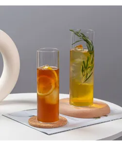 Detailansicht des langen geraden Glasbechers mit Getränk, Zitrone und Rosmarin auf Holzuntersetzer.