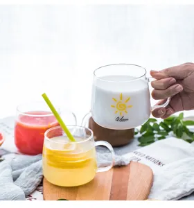 Clear heat-resistant glass water cup with handle and sun pattern detail for daily use.