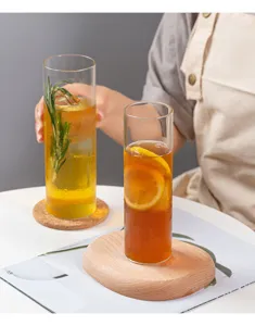 Detailansicht des hohen Hitzebestaendigen Glasbechers mit Getränk und dekorativem Holzuntersetzer.