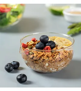 Clear heat-resistant glass bowl with pour spout, filled with yogurt, cereal, and fresh fruits.