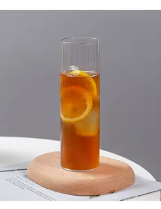 Nahaufnahme eines hohen zylindrischen Glases mit Eistee, Eiswürfeln und frischen Zitronenscheiben.