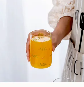 Nahaufnahme Detailaufnahme des klaren Glasbechers mit grünem Pflanzenmuster und frischem Saft.