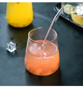 Dettaglio di un bicchiere di vetro trasparente con stampa e cannuccia, ideale per drink.