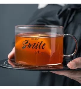Primo piano di tazza in vetro trasparente con stampa di lettere e tè caldo in ufficio.