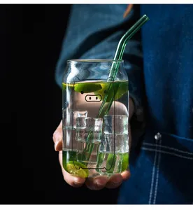 Creative transparent glass cup with cute pig design and green straw for cold drinks.