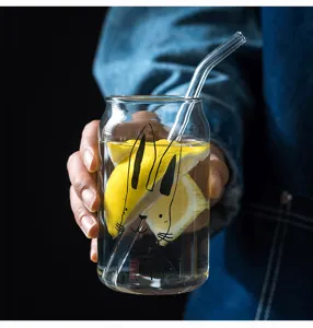 Clear glass can cup detail shot featuring cute rabbit print and glass straw with lemon water.