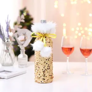 Close-up of Christmas gold sequin wine bottle cover with plush trim and yellow bow for holiday.