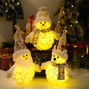 Close-up of glowing plush Christmas ornaments featuring Santa, snowman, and reindeer figures.