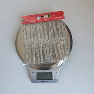 Vue détaillée de suspendre des glaçons en acrylique irisé de Noël pesés sur une balance.