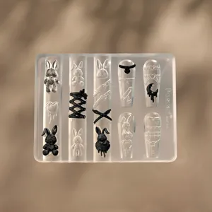 Detalle de molde de uñas de silicona transparente con dijes de conejito gótico de resina.