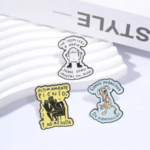Close-up detail of funny Spanish quote metal enamel pins with cute cartoon illustration designs.