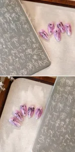 Detailed close-up of nail stamping plate with elegant bow designs and finished nail art