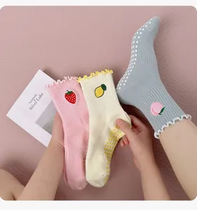 Detail view of women non-slip yoga socks with cute fruit embroidery and grip dots.