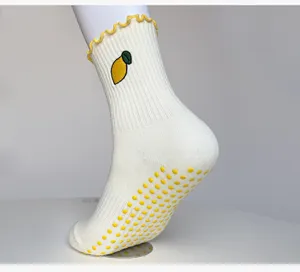Detail shot of white yoga socks with lemon embroidery, yellow ruffles, and anti-slip dots.