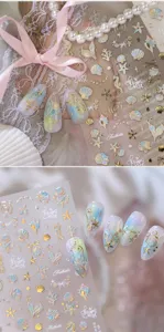 Nahaufnahme von 3D-Nagelstickern mit Ozean-Motiven wie Muscheln und Seesternen