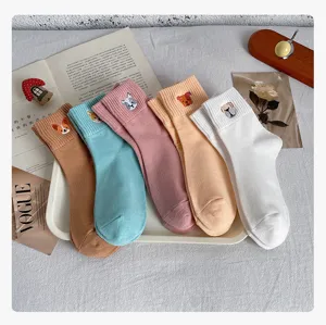 Detail view of cute embroidered dog cotton socks in candy colors displayed on a clean white tray.