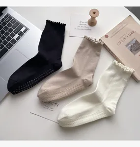 Detailed view of non-slip yoga socks featuring cute lace ruffles and grip dots on sole.